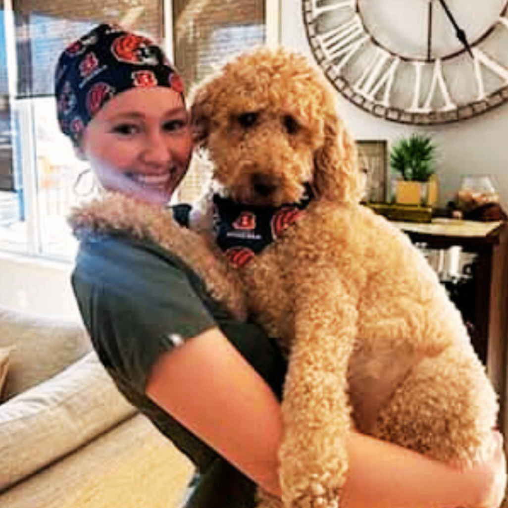 Nurse wearing jojo scrub cap and holding her dog